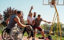 Persone che giocano a basket all’aperto, tra cui un atleta in sedia a rotelle