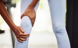 Persona che si tiene il ginocchio a causa di un dolore