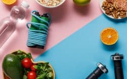 Attrezzatura sportiva e alimenti disposti su sfondo rosa e azzurro