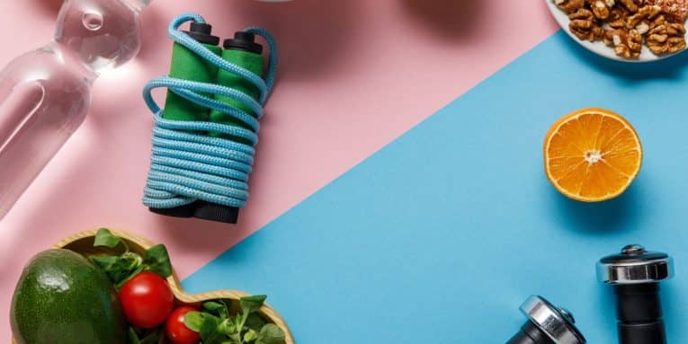 Attrezzatura sportiva e alimenti disposti su sfondo rosa e azzurro