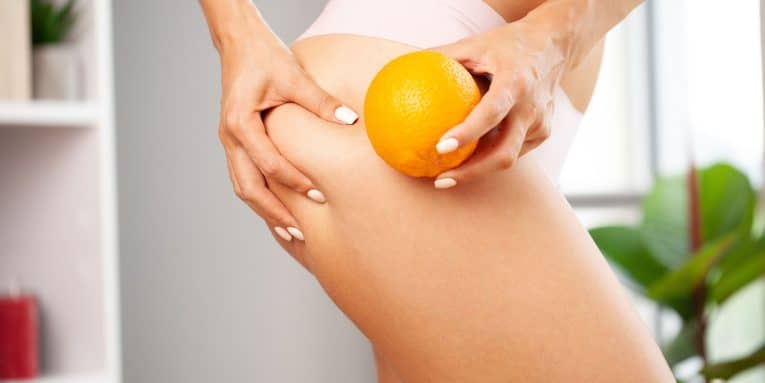 Mani che tengono un’arancia sulla coscia