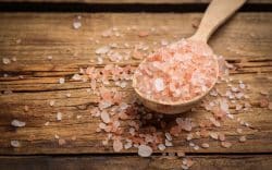 Cucchiaio di legno con sale rosa su tavolo in legno