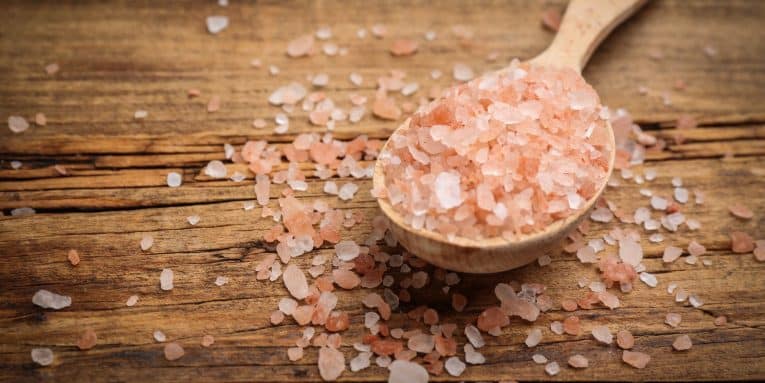 Cucchiaio di legno con sale rosa su tavolo in legno