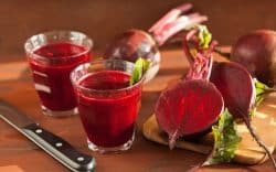Succo di barbabietola in bicchieri con barbabietole su tagliere in legno
