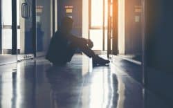 Persona seduta a terra in un corridoio in controluce
