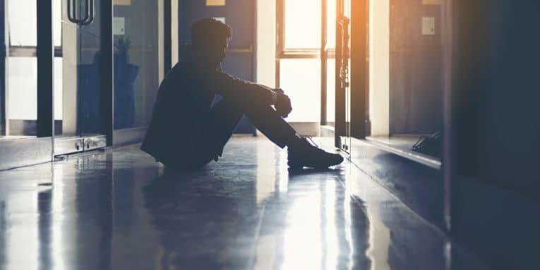 Persona seduta a terra in un corridoio in controluce