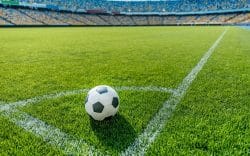 Pallone da calcio sul campo in uno stadio con tribune sullo sfondo