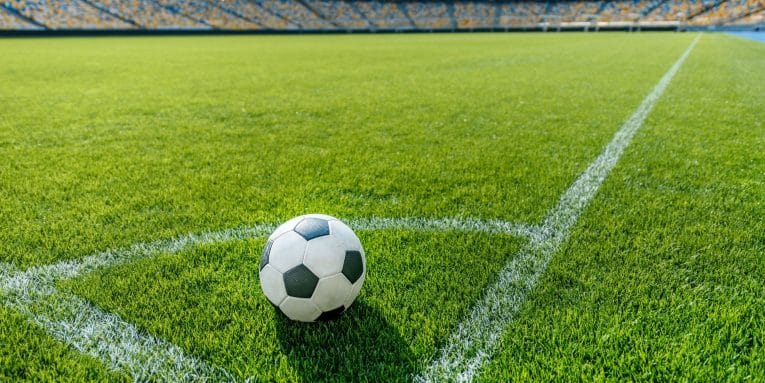 Pallone da calcio sul campo in uno stadio con tribune sullo sfondo