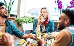 Gruppo di persone sedute a un tavolo mentre mangiano e ridono