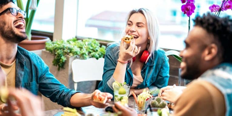 Gruppo di persone sedute a un tavolo mentre mangiano e ridono