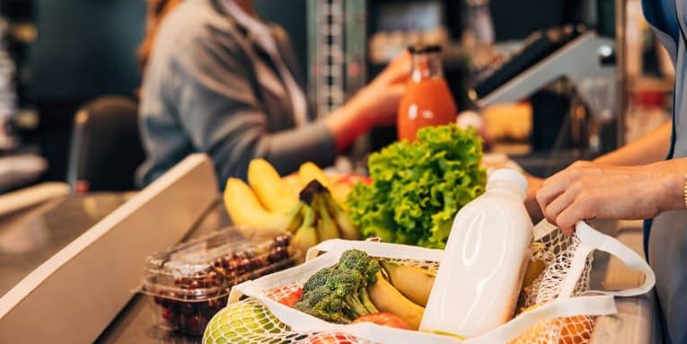 Borsa con spesa in rete appoggiata su una cassa al supermercato