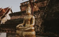 Statua dorata di Buddha seduto davanti a un tempio