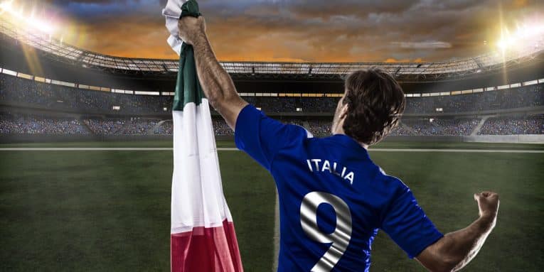 Calciatore con maglia dell'Italia che esulta nello stadio con bandiera italiana