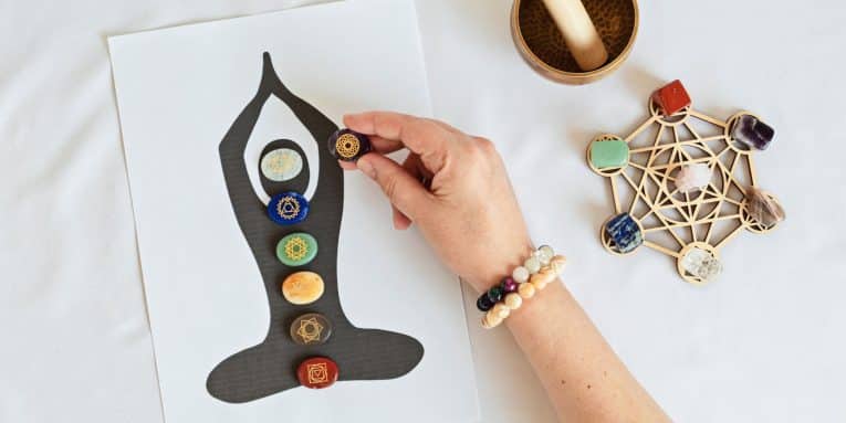 Mano che posiziona pietre dei chakra su una figura in meditazione
