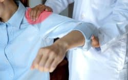 Dottore che tiene la spalla di un’altra persona mentre le muove il braccio