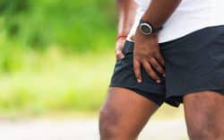 Sportivo che si tiene la coscia per dolore