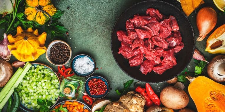 iotola con pezzi di carne cruda circondata da verdure crude e spezie