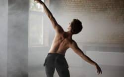 Ballerino di schiena che esegue un passo di danza in una stanza con luce naturale