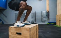 Persona che esegue un salto su box in palestra