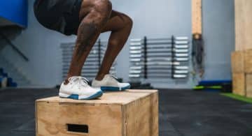 Persona che esegue un salto su box in palestra