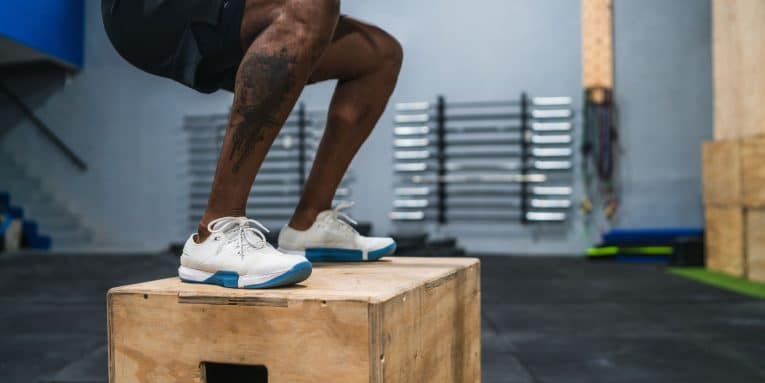 Persona che esegue un salto su box in palestra