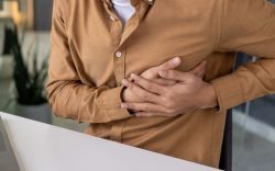 Persona seduta con mani sotto al petto in segno di dolore