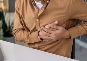 Persona seduta con mani sotto al petto in segno di dolore