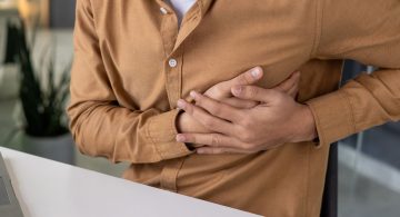 Persona seduta con mani sotto al petto in segno di dolore