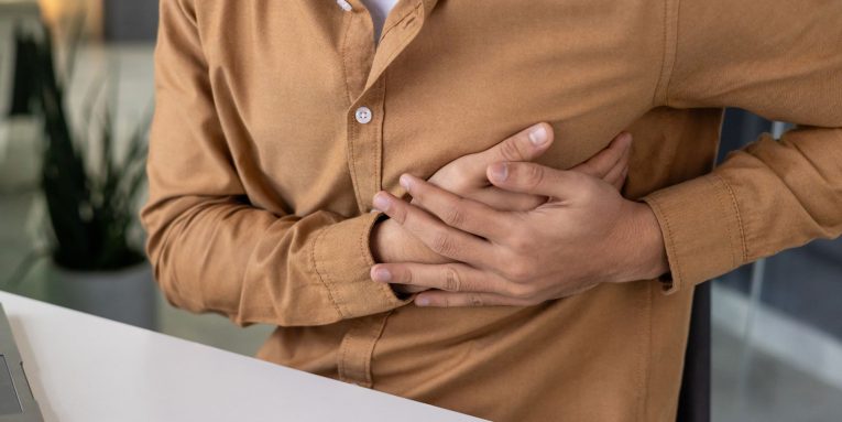 Persona seduta con mani sotto al petto in segno di dolore