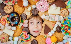 Bambina circondata da dolci e snack