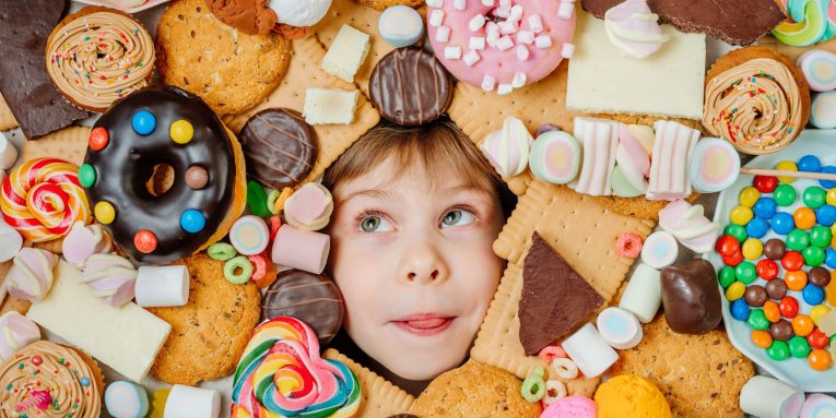 Bambina circondata da dolci e snack