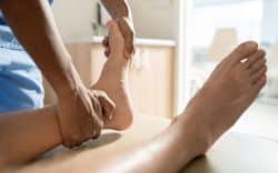 Operatore sanitario che manipola il piede di una persona durante trattamento