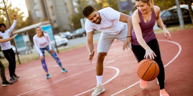 Persone che giocano a basket su campo all’aperto