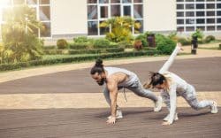 Uomo e donna che eseguono esercizi a corpo libero all’aperto