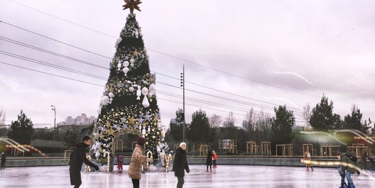 Persone che pattinano sul ghiaccio all’aperto vicino a un albero di Natale
