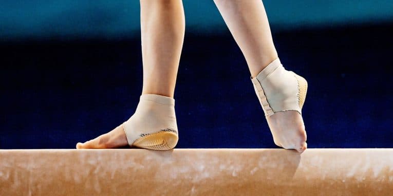 Gambe di ginnasta su trave con protezioni alle caviglie