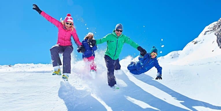 Persone che giocano e corrono sulla neve in montagna