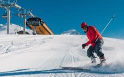 Sciatore in discesa su pista innevata battuta