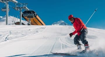 Sciatore in discesa su pista innevata battuta