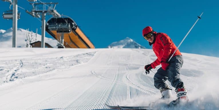 Sciatore in discesa su pista innevata battuta
