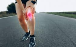 Runner con dolore al ginocchio durante corsa su strada