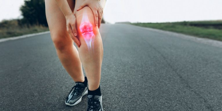 Runner con dolore al ginocchio durante corsa su strada
