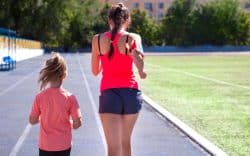 donna e bambina che corrono su pista di atletica