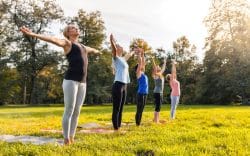 gruppo di persone che fanno esercizi su tappetini in un prato