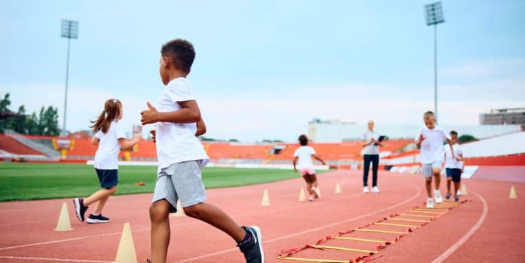 gruppo di bambini durante attività sportiva su pista di atletica