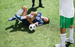 persona sdraiata su erba con una gamba piegata mentre si tiene il ginocchio