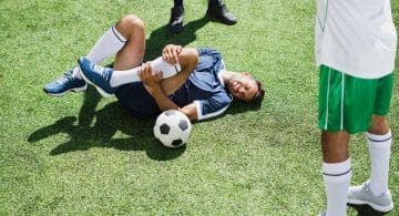 persona sdraiata su erba con una gamba piegata mentre si tiene il ginocchio