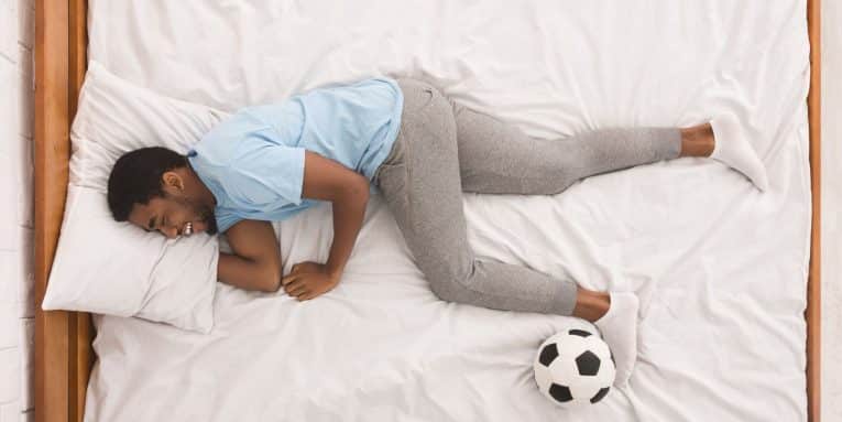 persona sdraiata su un letto con un pallone accanto