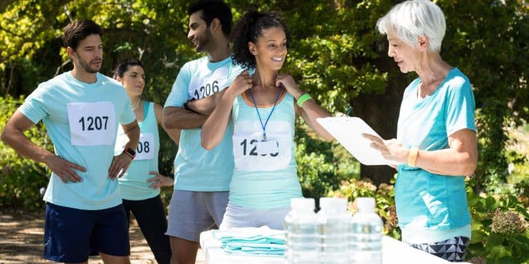 gruppo di persone con pettorine numerate mentre una persona tiene una cartellina