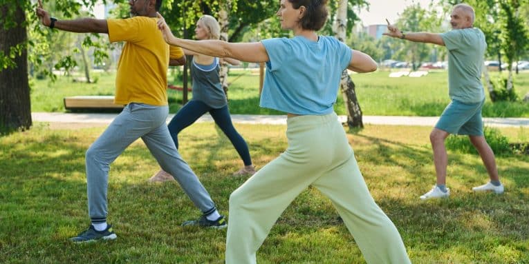 gruppo di persone con abbigliamento sportivo mentre fanno Tai Chi in un parco
